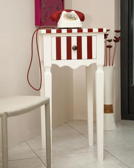 Mobile porta oggetti in legno laccato color avorio con strisce rosse, un cassetto e gambe lavorate